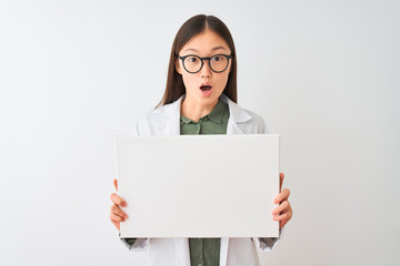 Young chinese dooctor woman wearing glasses holding banner over isolated white background scared in shock with a surprise face, afraid and excited with fear expression