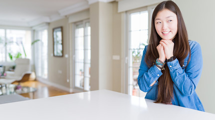 Young beautiful asian woman with long hair wearing denim jacket laughing nervous and excited with...