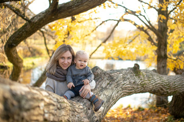 Naklejka na ściany i meble Young mother with her funny child posing in autumn park.