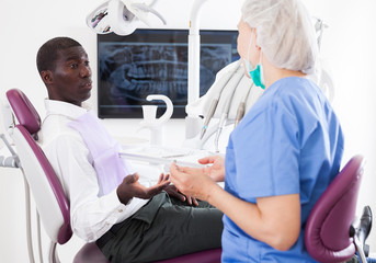 Professional positive doctor woman talking with patient in medical chair
