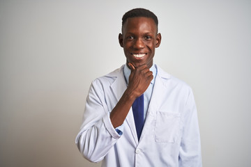 Young african american doctor man wearing coat standing over isolated white background looking confident at the camera with smile with crossed arms and hand raised on chin. Thinking positive.
