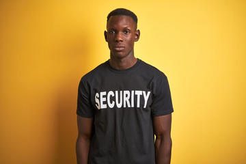 African american safeguard man wearing security uniform over isolated yellow background Relaxed with serious expression on face. Simple and natural looking at the camera.