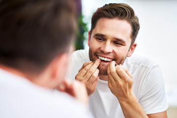 Adult man flossing teeth in the bathroom