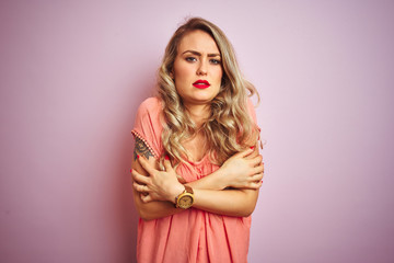 Young beautiful woman wearing t-shirt standing over pink isolated background shaking and freezing for winter cold with sad and shock expression on face