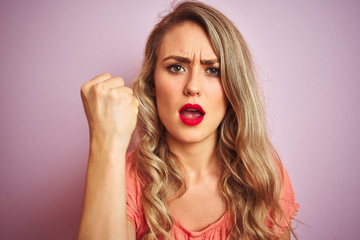 Young beautiful woman wearing t-shirt standing over pink isolated background annoyed and frustrated shouting with anger, crazy and yelling with raised hand, anger concept