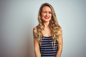 Obraz premium Young beautiful woman wearing stripes t-shirt standing over white isolated background winking looking at the camera with sexy expression, cheerful and happy face.