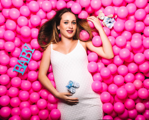 Fototapeta na wymiar Young pregnant woman playing in a pink ball pool