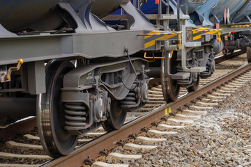 Close up detail of wheel, suspension and bearing system of freight train on steel railway track.