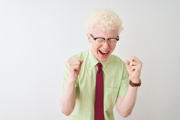 Young albino businessman wearing shirt and tie standing over isolated white background celebrating mad and crazy for success with arms raised and closed eyes screaming excited. Winner concept