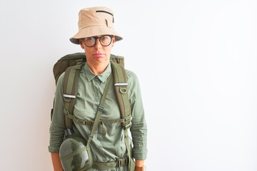 Middle age hiker woman wearing backpack canteen hat glasses over isolated white background depressed and worry for distress, crying angry and afraid. Sad expression.