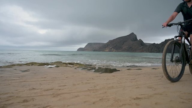 Close up of man on mountain bike who rides next to the sea