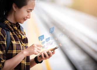 Beautiful asian girl Standing waiting for the train And she is using smartphone To find information on tourism. Travel and tourism concept.social media.