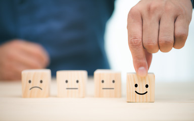 Hand of a businessman chooses a smiley face on wood block cube, The best excellent business...