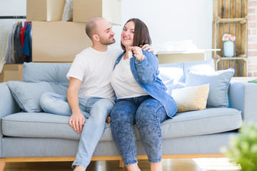 Young couple sitting on the sofa smiling very happy showing keys of new home, moving and buying new apartmet concept