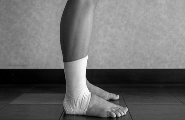 Black and white version of Side view of an Ankle tape job on an athlete’s ankle 