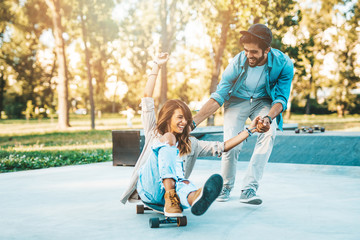 Beautiful young couple enjoying outdoors in city skateborading park