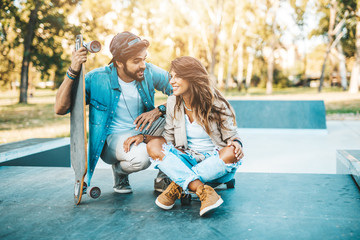 Fototapeta na wymiar Beautiful young couple enjoying outdoors in city skateborading park