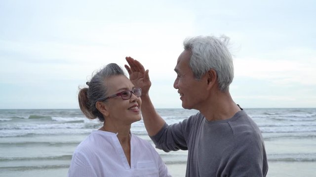 Asian couple senior elder retire resting relax kissing and hugging sunset beach honeymoon family together happiness people lifestyle, Slow motion footage