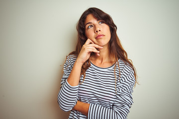 Young beautiful woman wearing stripes t-shirt over white isolated background with hand on chin thinking about question, pensive expression. Smiling with thoughtful face. Doubt concept.