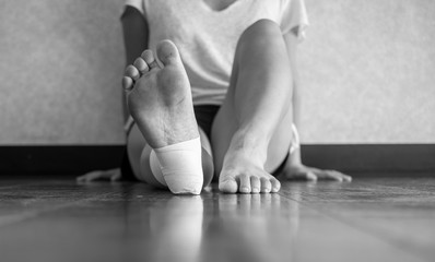 Black and white version of Injured athlete sitting down with an ankle tape job