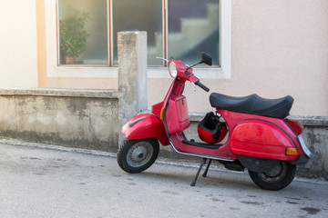 Red motor scooter in a cozy courtyard. European tourism. Background for calendar, advertisements and banners.