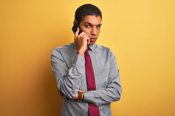 Young handsome arab businessman talking on smartphone over isolated yellow background with a confident expression on smart face thinking serious