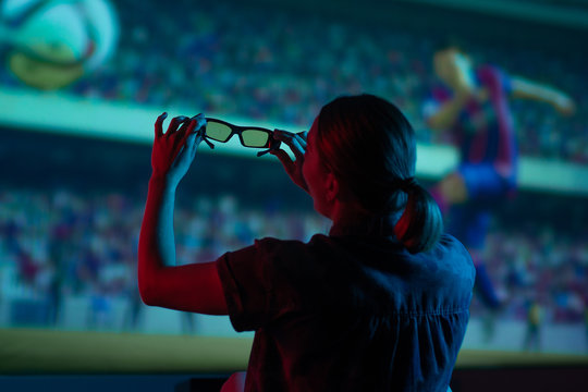 The girl is watching football, soccer in 3D, with glasses on the big screen. with entertainment and relaxation. action, rest in the cinema. Cheerleader, fan