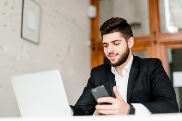 handsome businessman in a suit uses laptop in the office