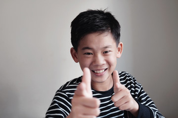 Smiling Asian preteen teenage boy pointing finger gun gesture, fun cheeky happy youth portrait