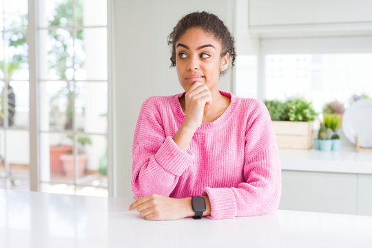 Beautiful african american woman with afro hair wearing casual pink sweater Thinking worried about a question, concerned and nervous with hand on chin