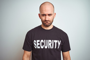 Young safeguard man wearing security uniform over isolated background skeptic and nervous, frowning...