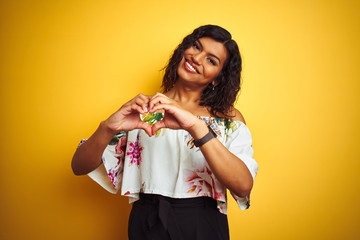Transsexual transgender woman wearing summer t-shirt over isolated yellow background smiling in love showing heart symbol and shape with hands. Romantic concept. - obrazy, fototapety, plakaty