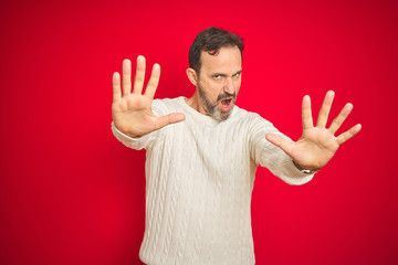 Naklejka premium Handsome middle age senior man with grey hair over isolated red background doing stop gesture with hands palms, angry and frustration expression