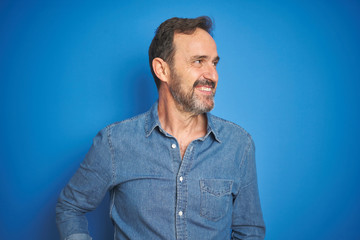 Handsome middle age senior man with grey hair over isolated blue background smiling looking to the side and staring away thinking.