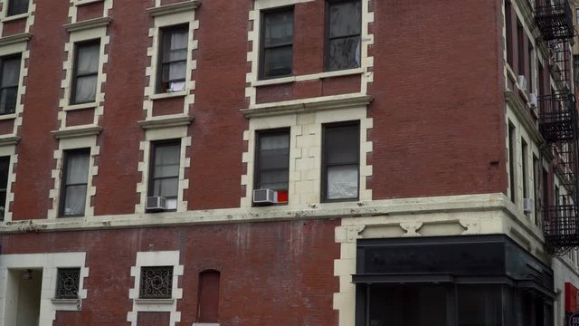 Typical New York City style brick apartment building day establishing shot 4k on street corner with rent control loft above generic bar restaurant location with blank signage for digital edit space dx