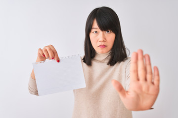 Young beautiful chinese woman holding notebook over isolated white background with open hand doing stop sign with serious and confident expression, defense gesture