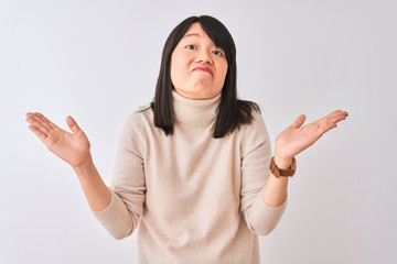 Young beautiful chinese woman wearing turtleneck sweater over isolated white background clueless...