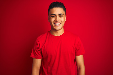 Young brazilian man wearing t-shirt standing over isolated red background with a happy and cool...