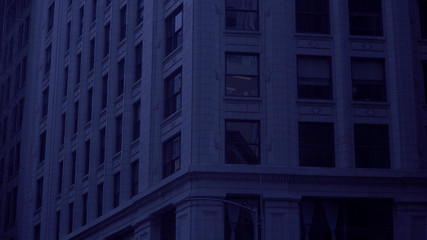 Night time establishing shot of generic typical urban city apartment or office building at night time under blue tint moon light.