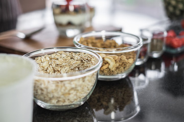 Glass bowls of nuts, grains, cereal and granola in a kitchen table.