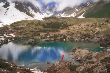 Hiking woman in red jacket stay at beautiful lake in mountains.