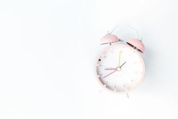 Vintage alarm clock pink color on white background. Rest hours time of life good. Flat lay, top...