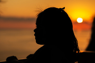 a little girl on the balcony overlooking the sea and the sunset. Silhouette against the sun. the concept of tourism, recreation