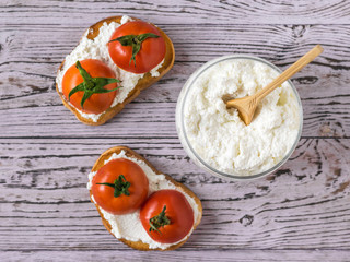 Two toast with tomatoes and cottage cheese on a wooden table. The view from the top. Flat lay.