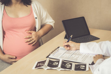 Happy pregnant woman visit gynecologist doctor at hospital or medical clinic for pregnancy consultant. Doctor examine pregnant belly for baby and mother healthcare check up. Gynecology concept.