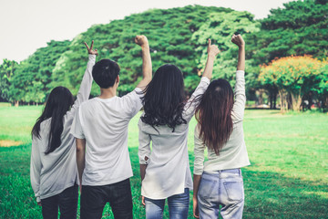 Young happy students of men and women raising hands celebrating and showing teamwork in the park of...