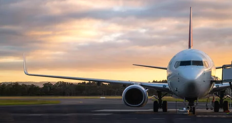 Fototapeten Blick auf den Sonnenuntergang des Flugzeugs auf der Landebahn des Flughafens unter dramatischem Himmel in Hobart, Tasmanien, Australien. Luftfahrttechnologie und Weltreisekonzept. © Summit Art Creations