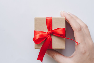 Woman holding gift box with red ribbon.