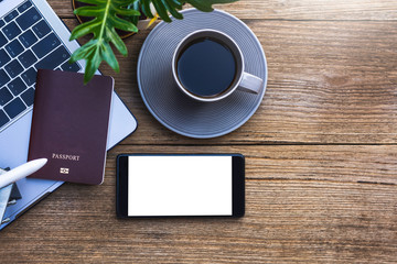 Obraz na płótnie Canvas Mobile smartphone,passport, laptop ,airplane and cup of coffee mock up design template isolated on wooden table background. Business and technology concept. Clipping path and copy space.Top view