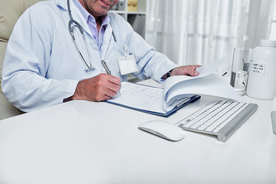 Cropped image of general pratitioner filling document with medical history of patient